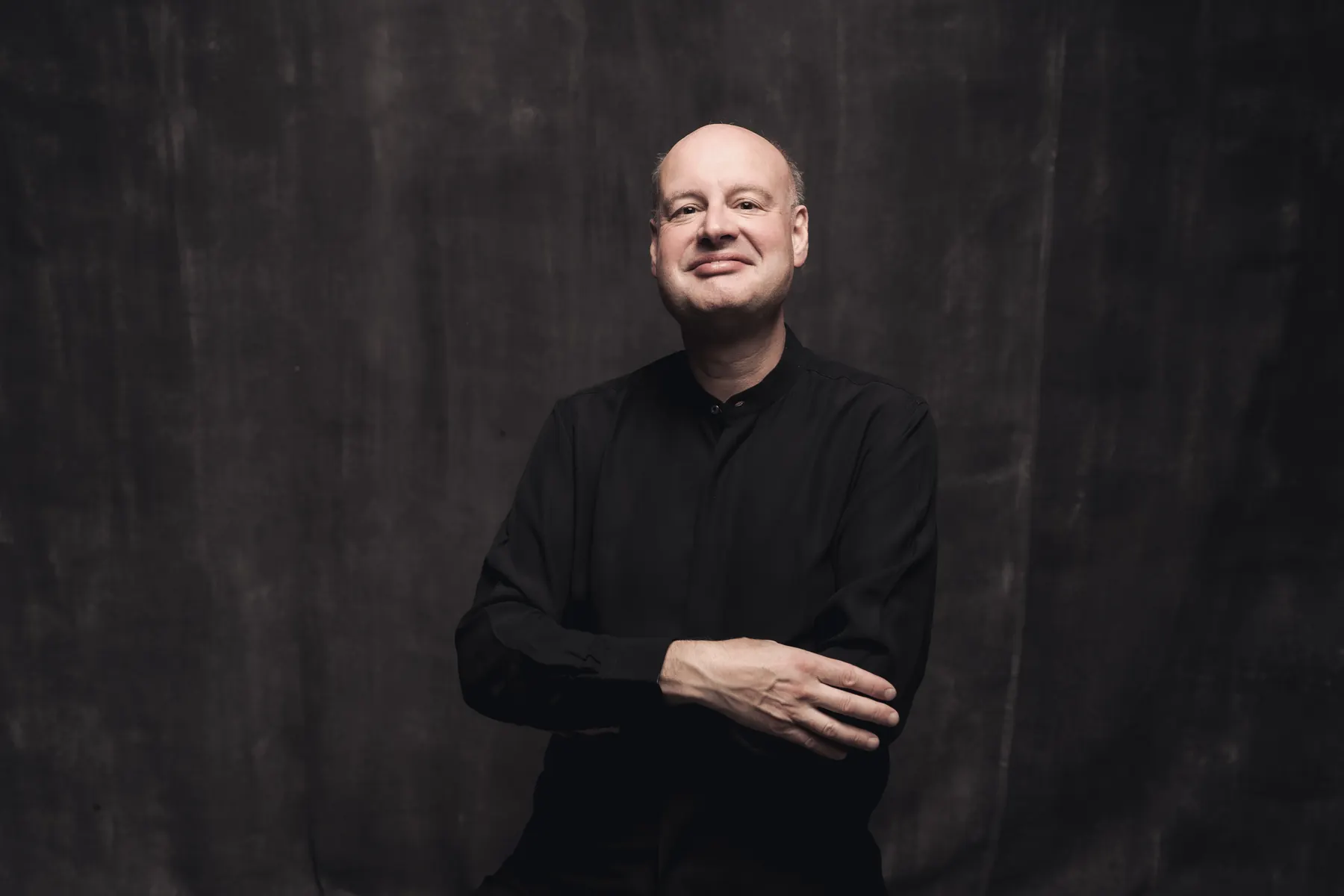 Stephen Layton, nasmejan, s prekrižanimi rokami